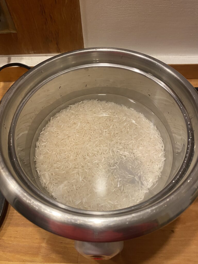 basmati rice and water in a stainless steel rice cooker pot