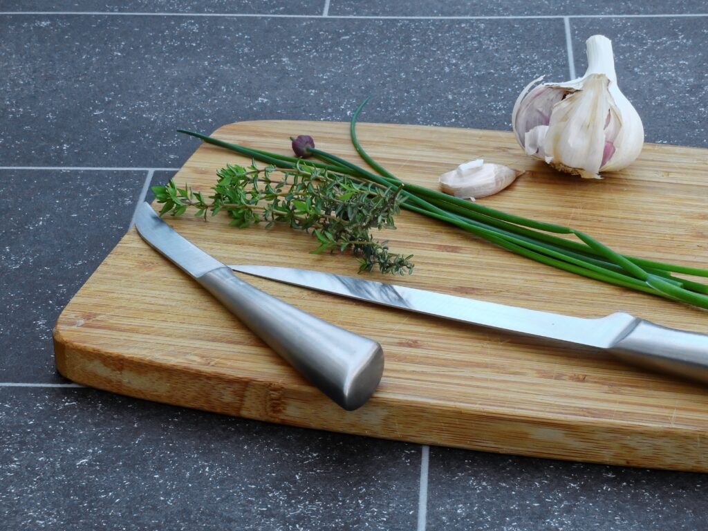 Garlic, chives, and leeks on a cutting board with a knife (DIY mortar and pestle)